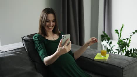 Pregnant-woman-video-chatting-on-mobile-phone-at-home,-slow-motion