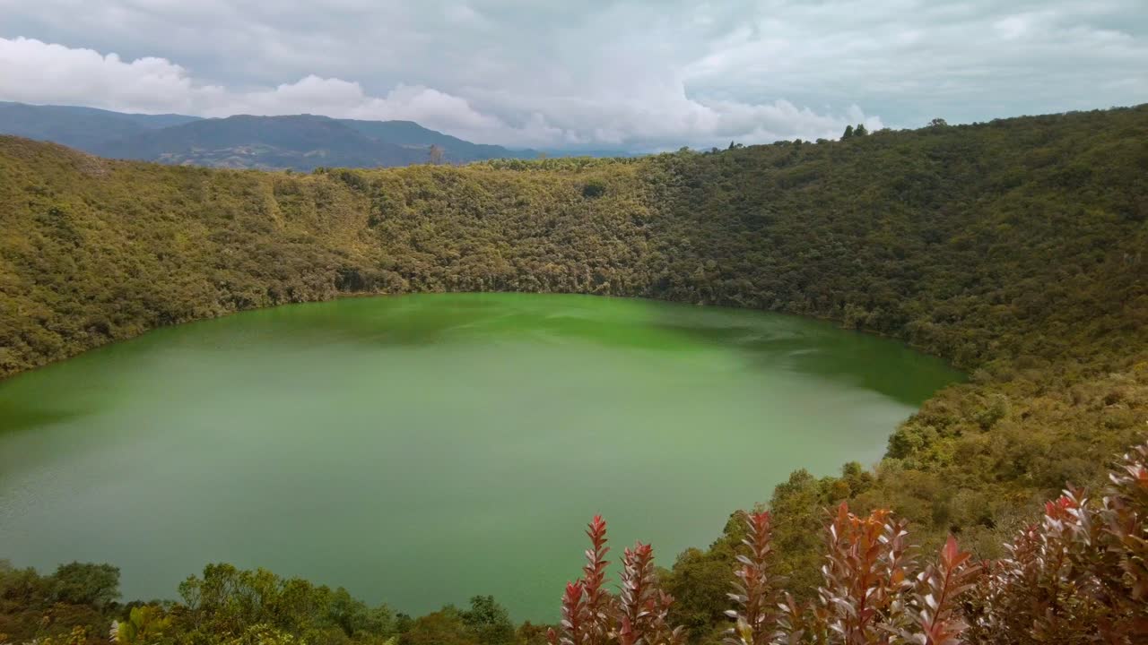 Slow panning shot of sunlight beaming down over Guatavita Lake in Colombia