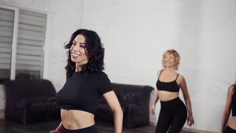 a group of attractive female dancers in the ballroom practising bachata basic moves. sexy women in black active wear enjoing latin dance.