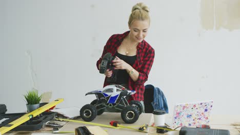 Woman-playing-with-radio-controlled-car-in-workshop