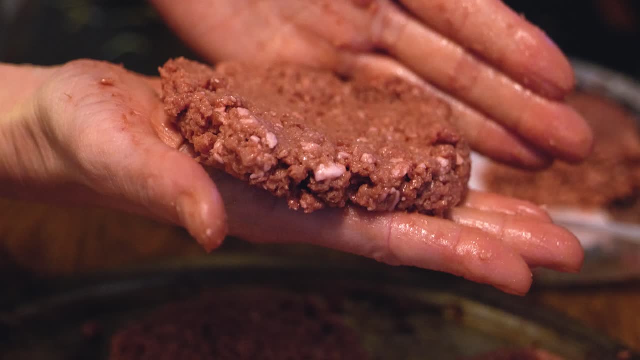 Plant based Impossible Burger meat patties un-cooked being prepared and formed shaped by white caucasian hands to be cooked and grilled - in Cinema 4k (30fps slow from 60fps).