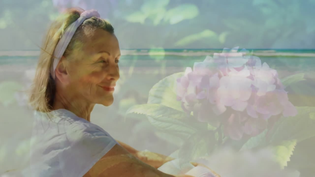 Inquadratura di profilo che fonde una fioritura di ortensia sul mare, con una donna anziana sorridente che inala per la salute.