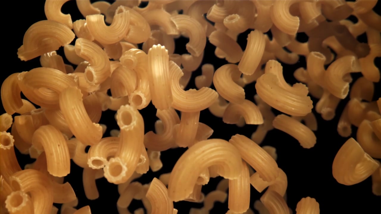 Pasta Maccheroni Cruda che Cade al Rallentatore su Sfondo Nero.