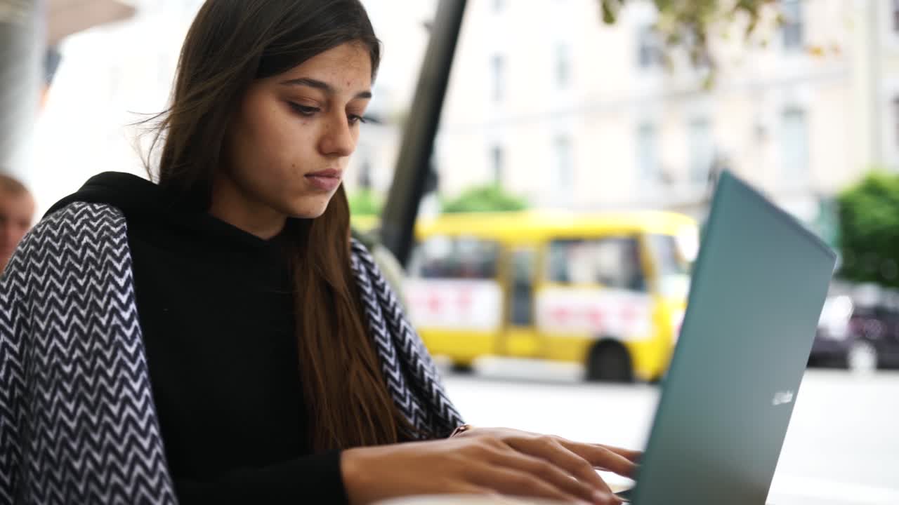 mujer joven trabajando en una computadora portátil en un café