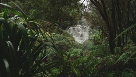 Atemberaubende-Zeitlupe-Der-Rohen-Kraft-Des-Wasserfalls-Im-Neuseeländischen-Wald-Rotorua,-Dampfende-Geothermische-Weitwinkelaufnahme