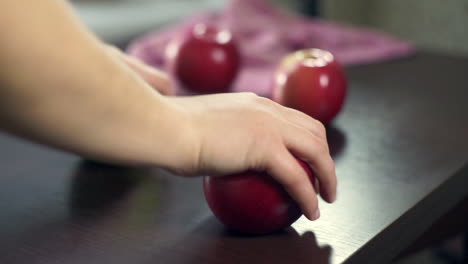 hand take red apples from wooden table. fresh fruits. vegetarian food