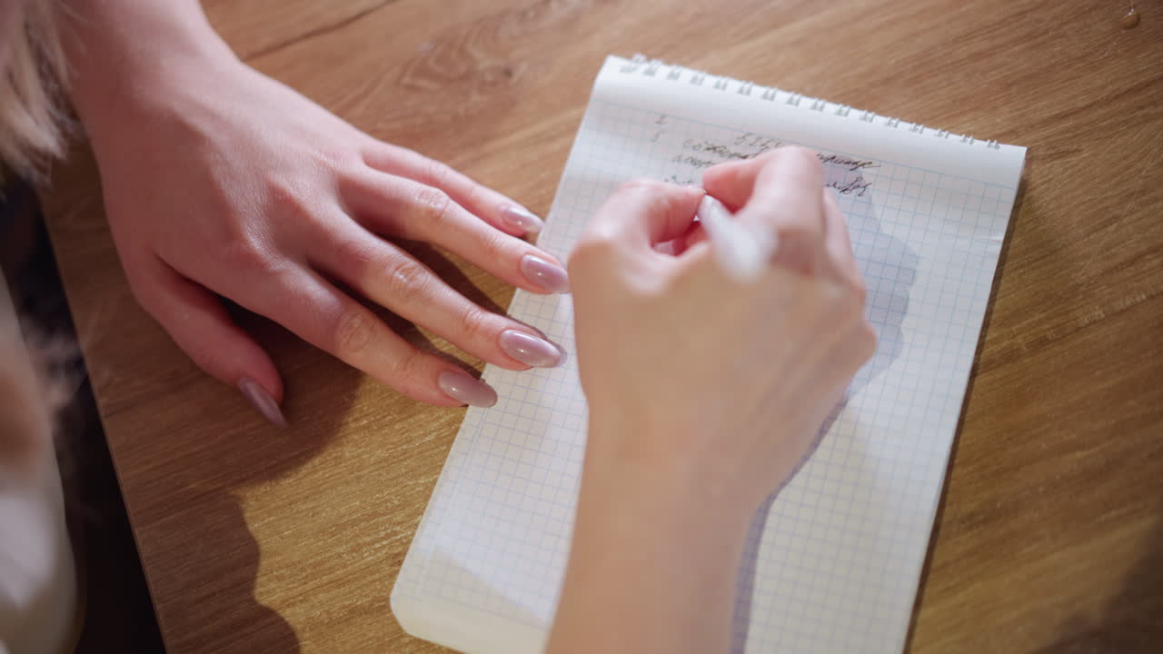 Close-up of woman writing with pen in notebook on wooden table, focusing on neat handwriting and creative process, practicing journaling, planning, organizing ideas, reflecting thoughts, mindfulness