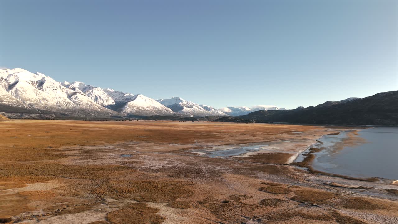 Wide Patagonian landscape with snow-covered Andes mountains in the background and dry plains in foreground