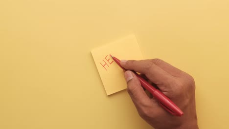 hand writing "help" on a yellow sticky note