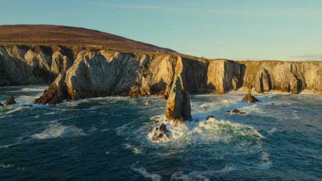 the white cliffs of ashleam lighting up during sunset while waves are the breaking on the rocks