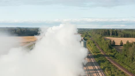 Aerial-fly-over-drone-shot-of-wooden-briquette-factory-spewing-fumes-in-rural-area