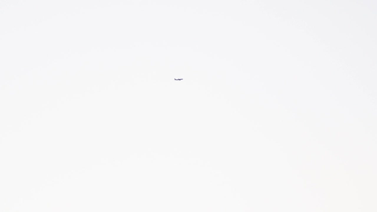 Vista di un aereo che vola nel cielo bianco - ripresa dal basso.