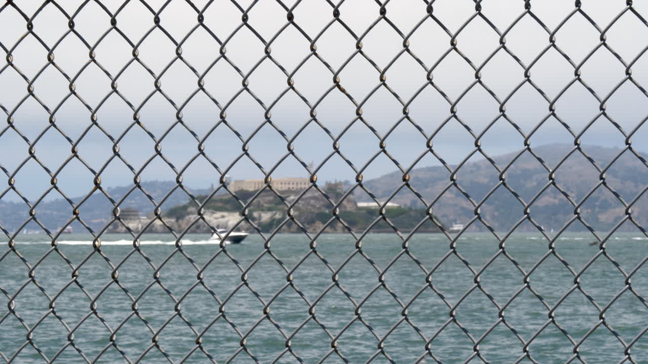 Alcatraz in soft focus behind a steel wire mesh fence in foreground