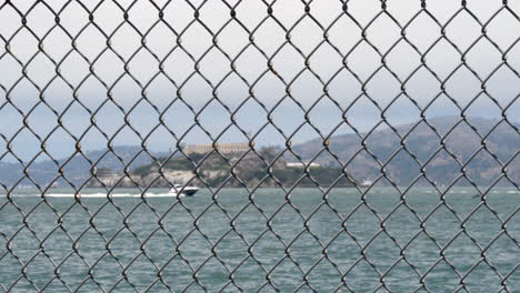 alcatraz in soft focus behind a steel wire mesh fence in foreground