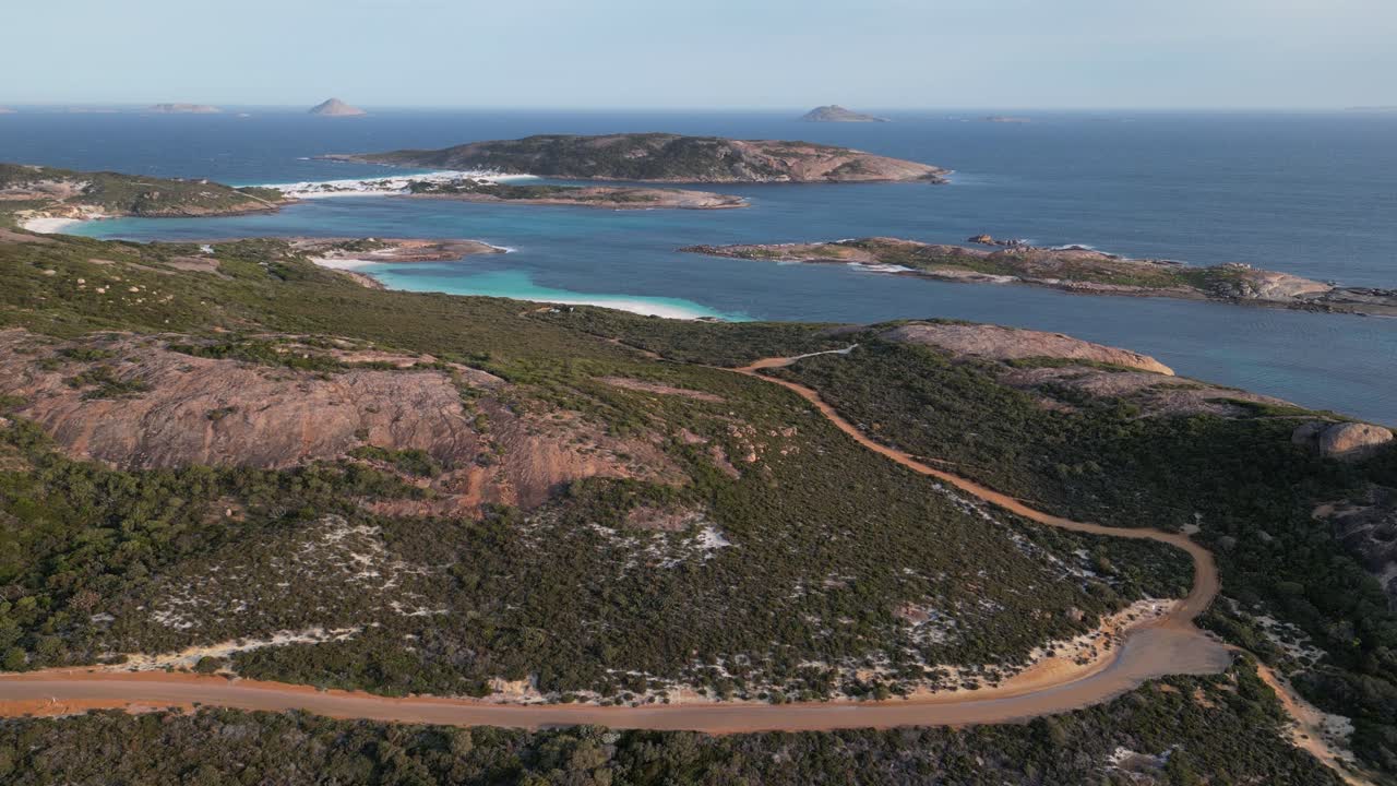 Sentieri collinari verso la spiaggia di Wharton con isole in mare e orizzonte, ripresa aerea con jib in ascesa