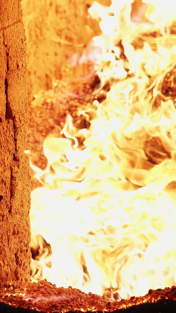 Burning wood chip pellets a renewable source. Burning wood chip pellets a renewable source, modern wood-burning stove to heat house in winter. Vertical video