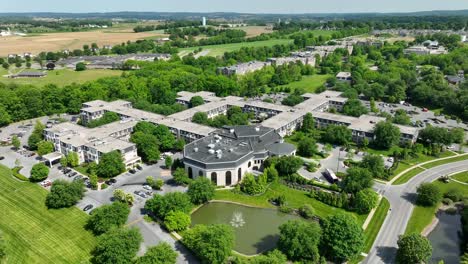 Panoramic-view-of-an-expansive-apartment-complex-community-surrounded-by-beautiful-landscaping-next-to-a-small-lake-with-a-fountain