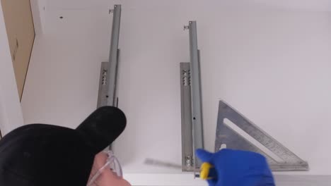 a qualified master in gray overalls installs furniture in a modern bright kitchen a qualified master in gray overalls installs furniture in a modern bright kitchen
