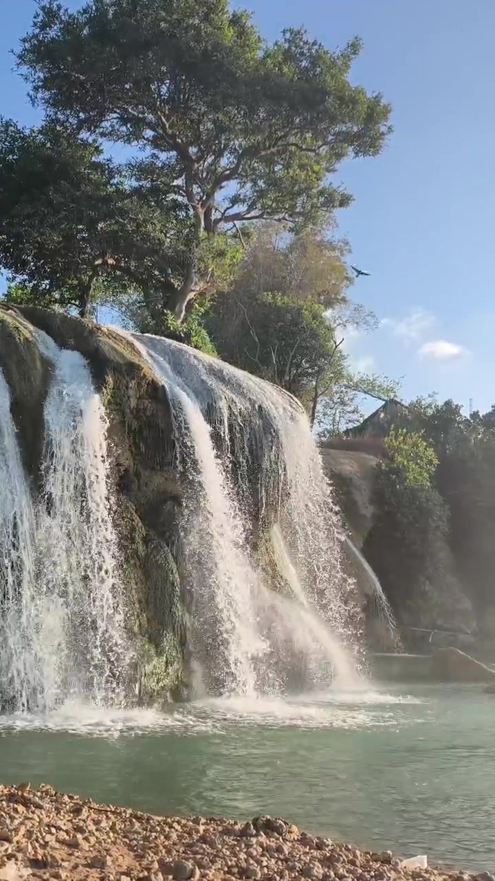 Cascata panoramica che si getta in un fiume tropicale.