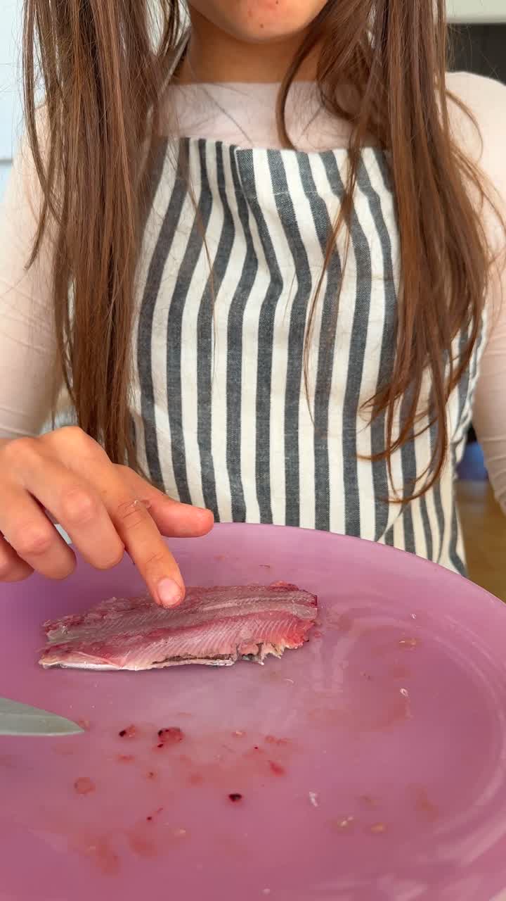 Hands preparing fish fillets on a pink cutting board