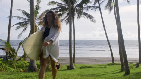 femme marchant et tenant une planche de surf