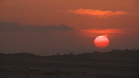 an orange ball of sun sets behind the la hills
