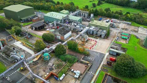 Aerial-footage-approaches-a-large-industrial-chemical-plant-in-the-UK,-revealing-pipelines,-metal-structures,-cooling-towers,-and-chemical-storage