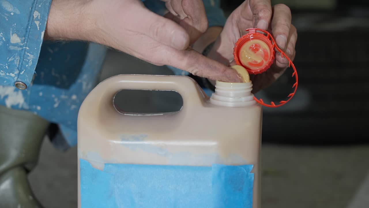 Man removes cap of eco friendly lanolin rustproofing product for vehicle undercarriage during winter, touches to demonstrate non toxic qualities