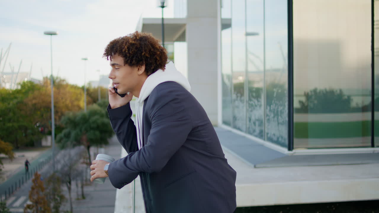 Curly hipster calling smartphone glass balcony close up. Student holding tea cup
