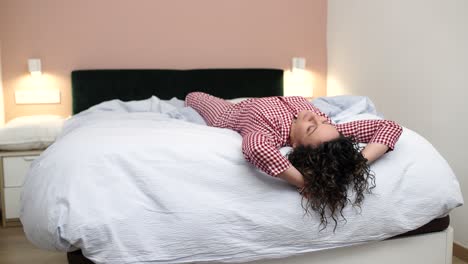 Woman wearing pajamas lying on bed changing position