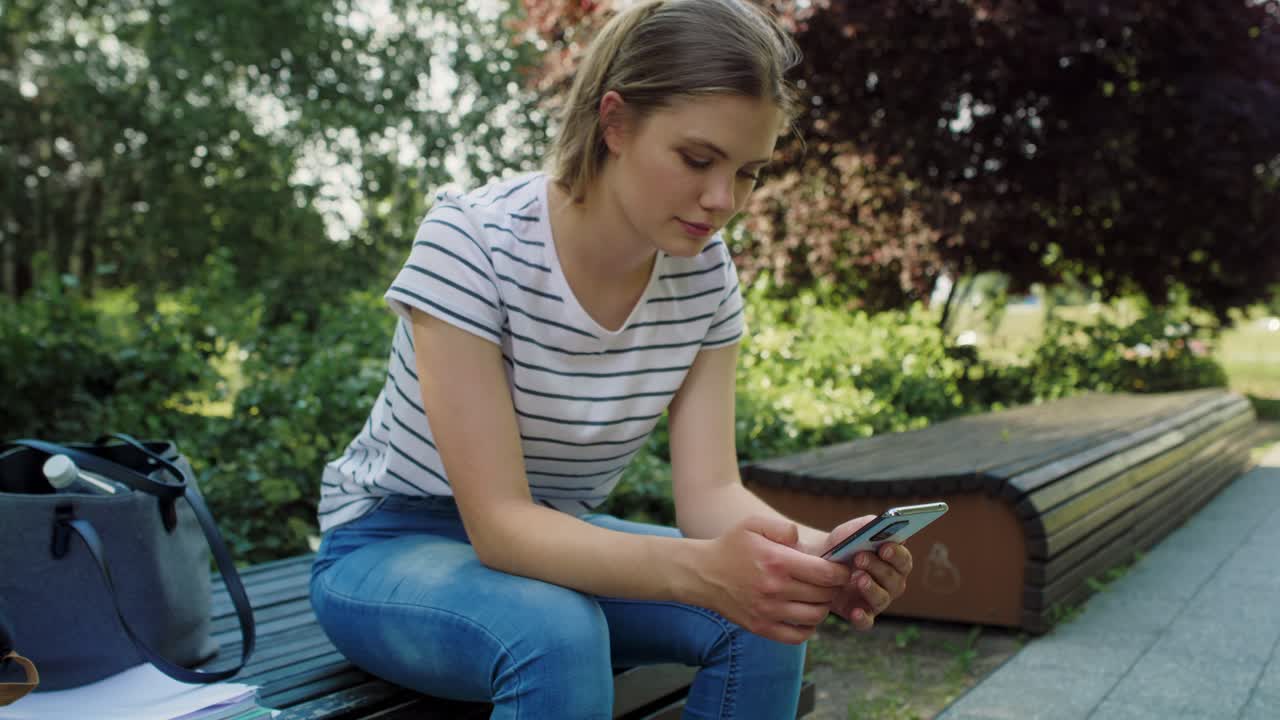 Caucasian female student browsing mobile phone outdoors