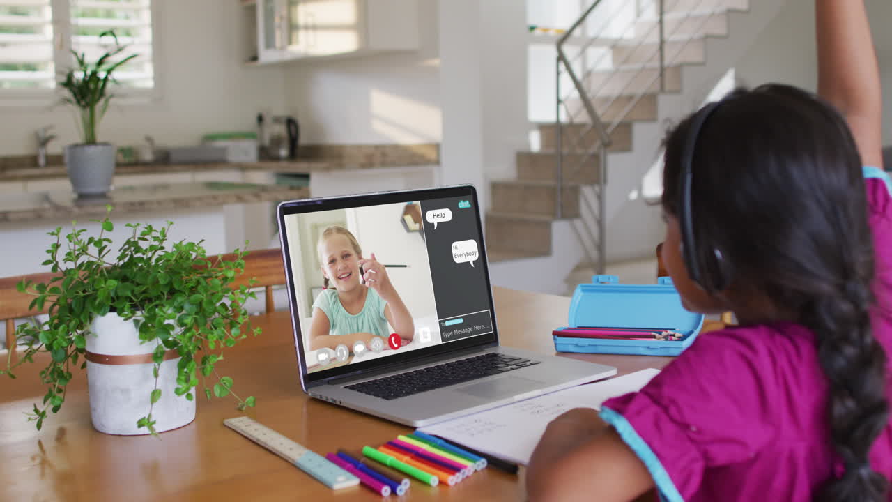 Schoolgirl using laptop for online lesson at home, with her colleague and web chat on screen