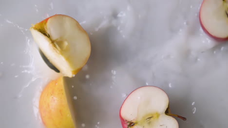 rodajas de manzana cayendo en agua lechosa con salpicaduras en cámara lenta