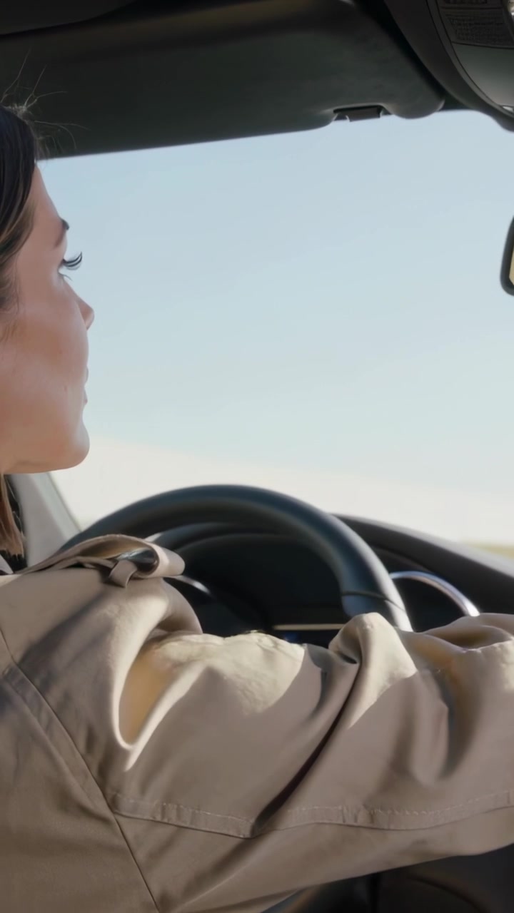 Video verticale: Donna in trench che guarda a sinistra e regola il volante in auto per mantenere la corsia
