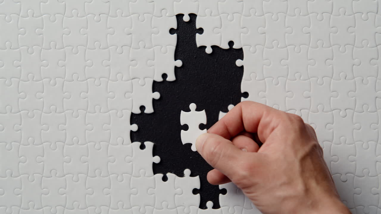 Fingers placing jigsaw segment completing puzzle structure on black closeup