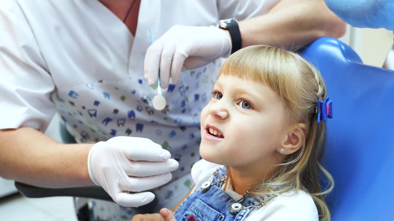 Little girl sitting in a chair shows the dentist teeth. Visit to the dental clinic