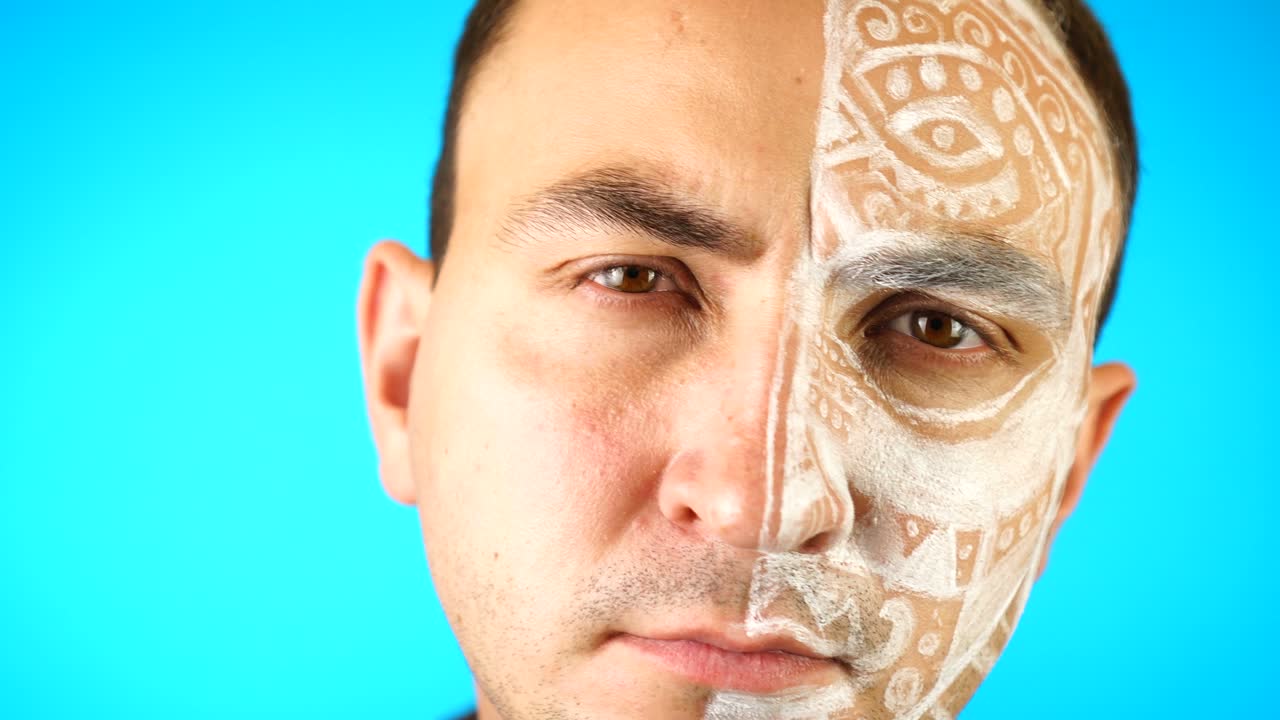 얼굴이 칠해져 있고 의심스러운 표정으로 파란 바탕을 쳐다보고 있는 남자