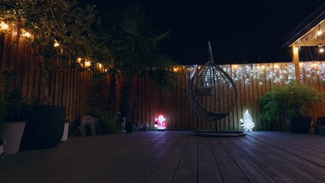 outdoor footage of a minimalistic garden at night with warm lighting, fairy lights and christmas decorations