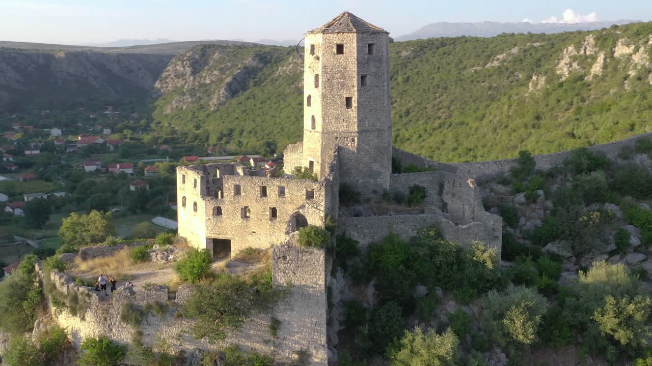 Abandoned castle over village on top of mountain. Panning shot, drone flight