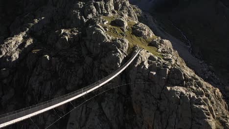 Tiro-Giratorio-De-Una-Sola-Persona-Que-Conquista-El-Miedo-A-Las-Alturas-Caminando-Sobre-Un-Estrecho-Y-Largo-Puente-Colgante-Durante-Una-Caminata-En-Los-Alpes-Suizos-En-Un-Día-Caluroso-Y-Soleado