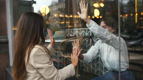 friends greeting through a cafe window during covid-19 pandemic