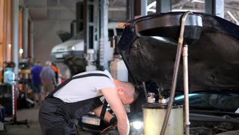 an individual examines a vehicles engine inside a buildings garage