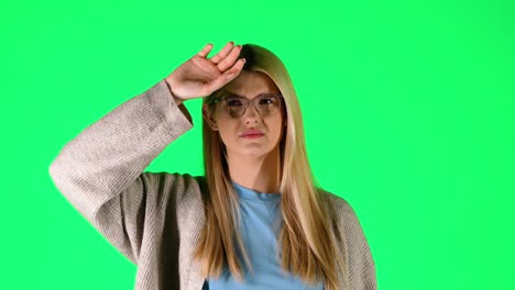 Blonde-Junge-Kaukasische-Frau-Mit-Brille-Niest-Kalt-In-Einem-Studio-Portrait-Mit-Unendlich-Grünem-Hintergrund