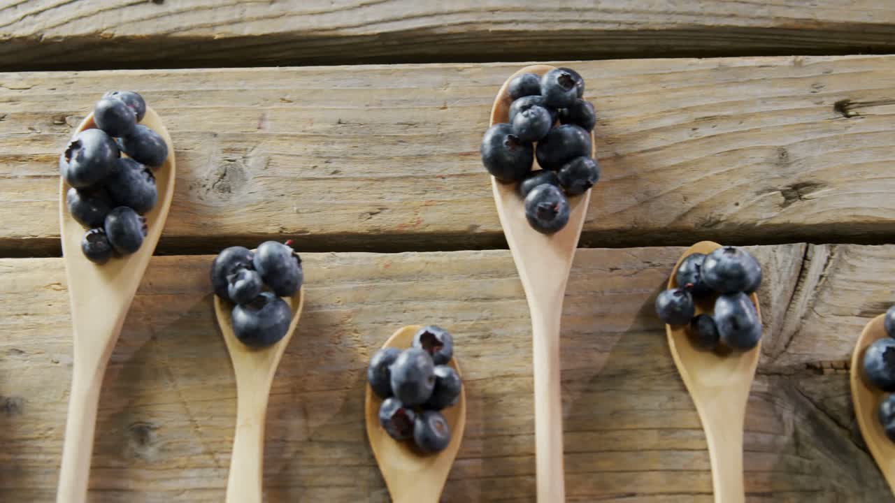 Spoons of blueberries arranged on wooden table 4k