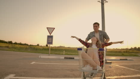 Gente-Alegre,-Una-Pareja,-Un-Hombre-Y-Una-Mujer-Al-Atardecer,-Viajan-En-Carritos-De-Supermercado-En-Cámara-Lenta.