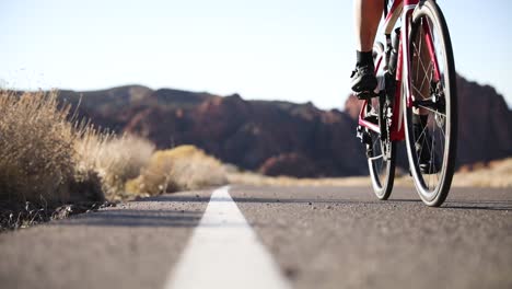 male cyclist on road bike on path in southwest utah desert in moab, ground-level