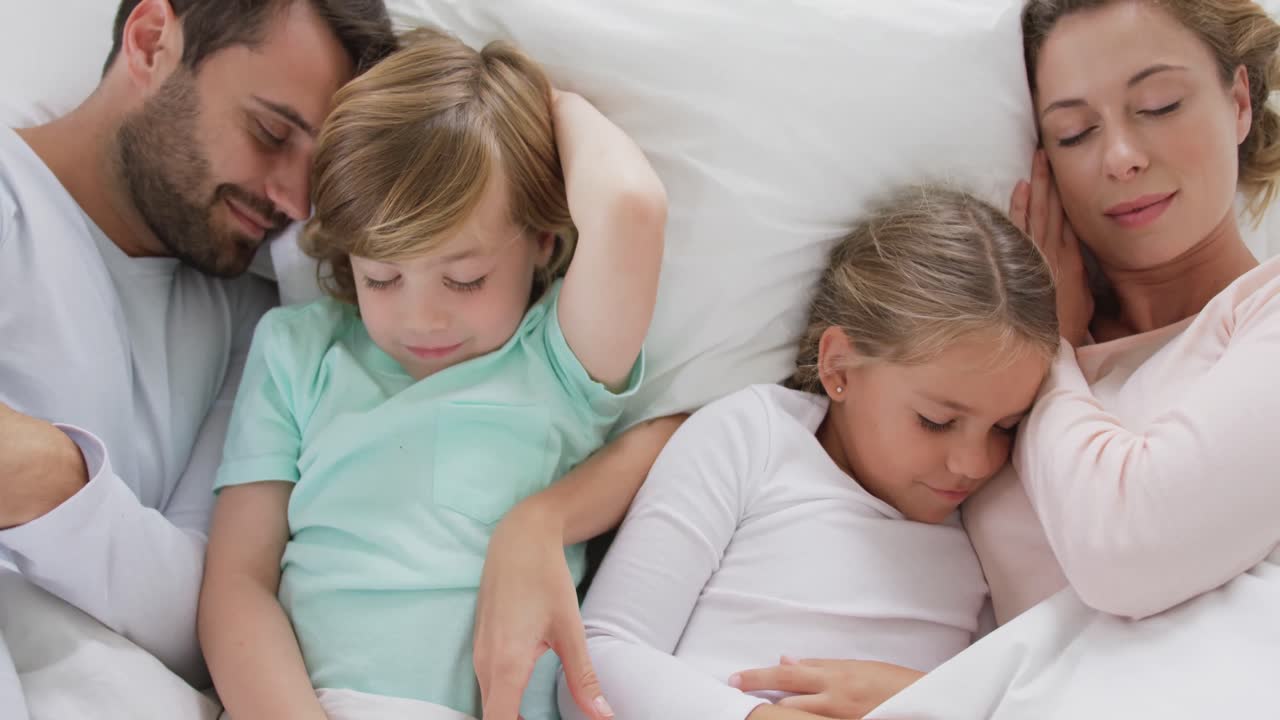 Family sleeping together on bed in bedroom at comfortable home 4k