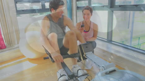 Animation-of-financial-data-processing-over-caucasian-man-exercising-with-female-trainer-on-gym