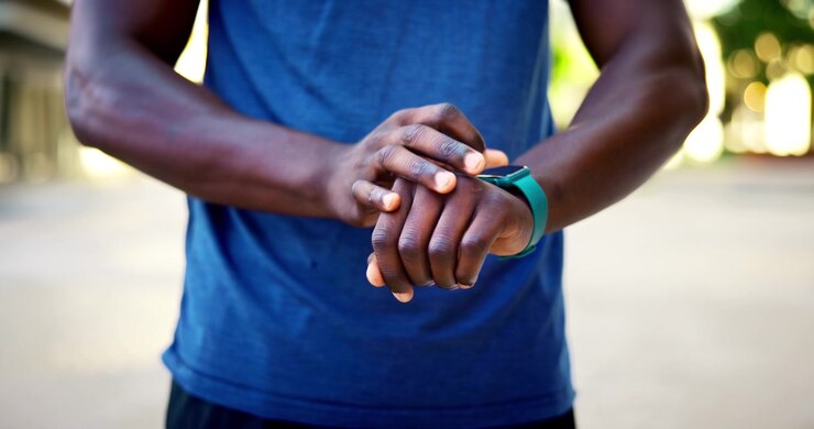 Uomo atletico che controlla il suo smartwatch durante un allenamento all'aperto