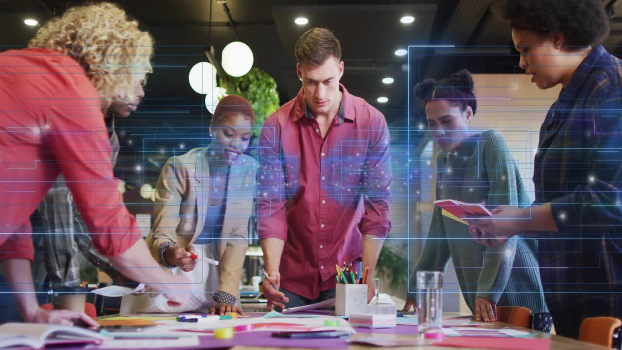 Team lead pointing while team arranging mockups on table, digital grid overlay guiding design